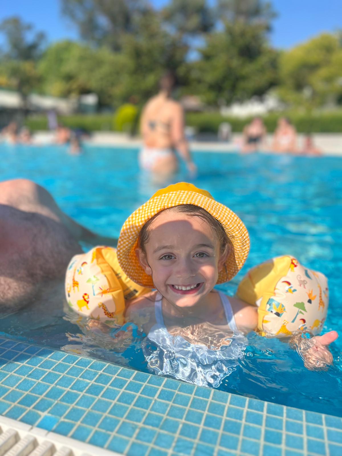 Menina na piscina com chapéu amarelo