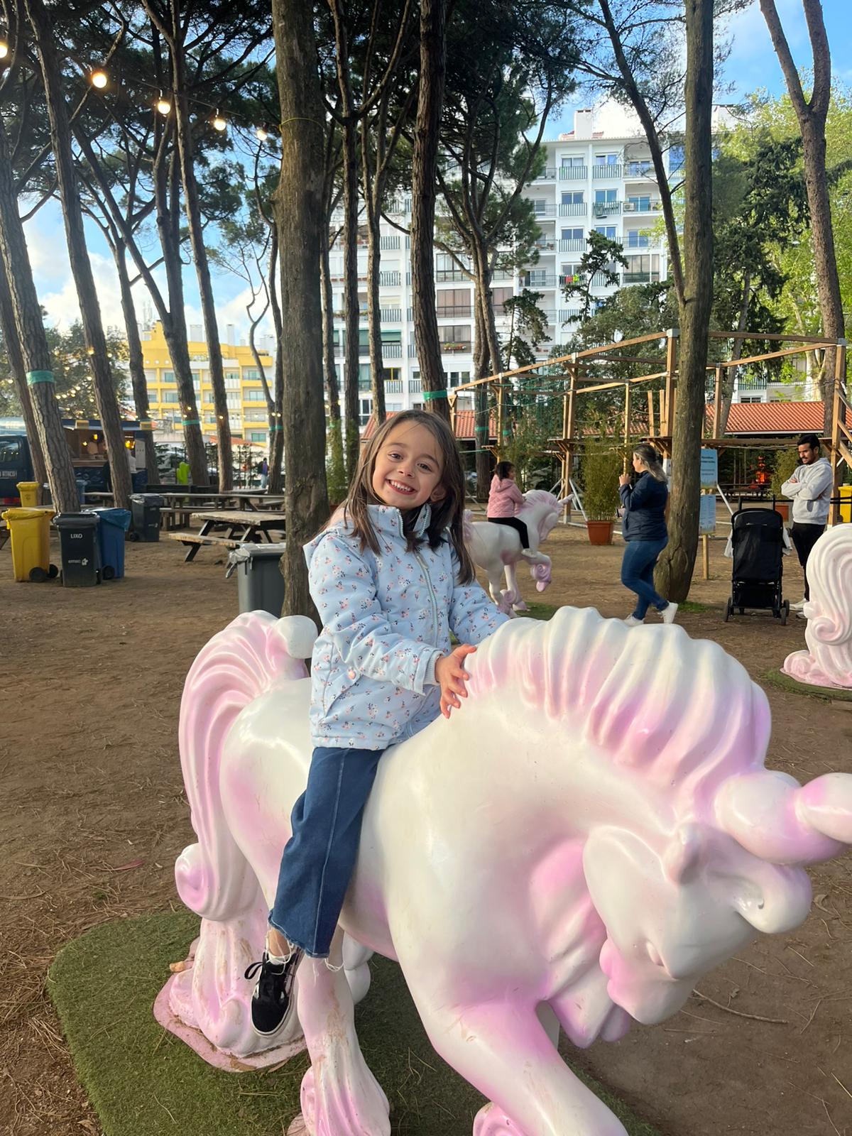 Menina a andar de unicórnio no parque